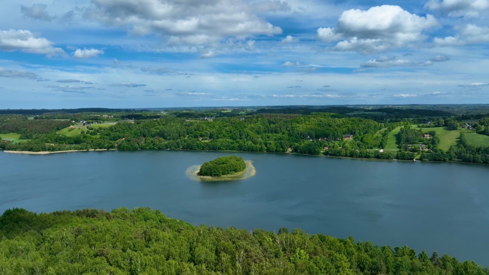 Jezioro z wyspą wśród lasów Szwajcarii Kaszubskiej z lotu ptaka