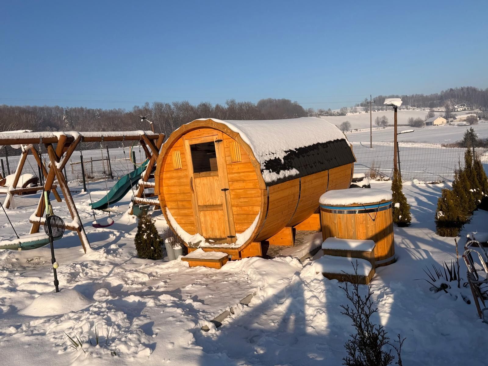 Sauna-beczka i balia w śniegu, w zimowym słońcu